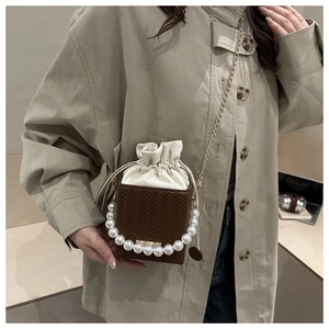 Detailed side view of mini bucket bag with pearl handle and woven leather texture