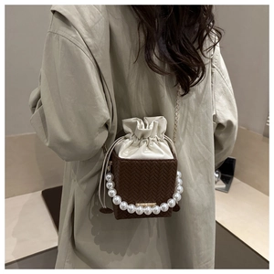 Vue détaillée du mini sac seau tissé avec poignée en perles et fermeture à cordon