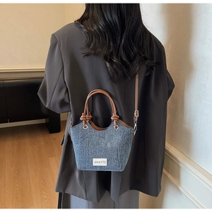 Dettaglio borsa a tracolla in denim vintage con cinturini in pelle marrone ed etichetta