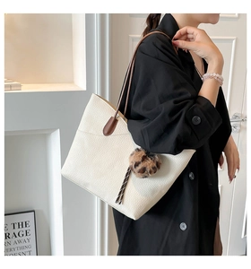 Detail of creamy white tote bag featuring lychee grain texture and leopard plush charm