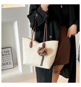 Detail of cream white lychee texture tote bag with brown straps and leopard heart charm