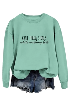Détail d'un sweat vert menthe avec épaules tombantes et texte noir imprimé sur le devant