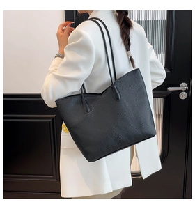 Close-up of black pebble leather tote bag worn as an underarm shoulder bag by model