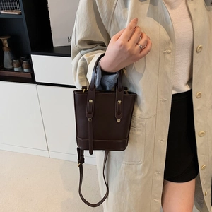 Dark brown leather bucket bag with gold rivets and adjustable shoulder strap for women
