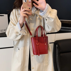 Minimalist red leather bucket bag with rivet details and crossbody strap for women
