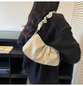 Dettaglio della tracolla a pieghe e finitura metallica della borsa chic da donna