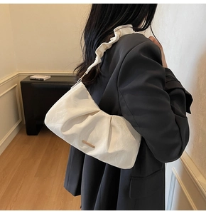 Detail of cream white pleated cloud bag with elegant ruffled strap and metal logo