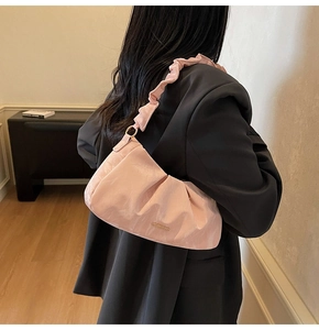 Dettaglio borsa nuvola rosa chiaro con tracolla arricciata e placca in metallo oro