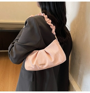 Close-up of pink ruched cloud bag with silk texture and decorative golden logo plate