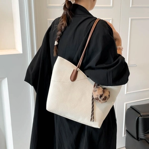 Off-white pebbled leather tote bag with brown straps and leopard pom-pom charm