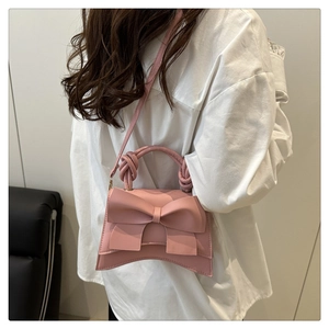 Detailed view of pink bow handbag with woven handle and elegant curved base design