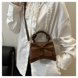 Detail of dark brown leather handbag with large decorative bow and knot handle