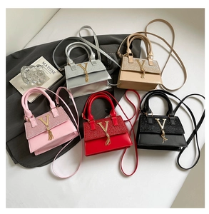 Detalle de cinco mini bolsos de mano con paneles brillantes, logo V y borlas suaves