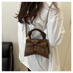 Detail showing the large decorative bow and knotted handle on dark brown PU handbag