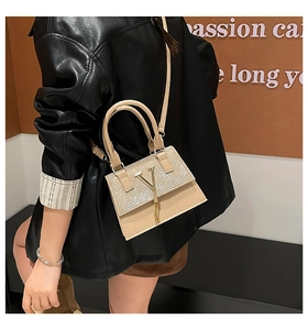 Detail of beige leather crossbody bag with sparkling rhinestones and golden V-logo tassel