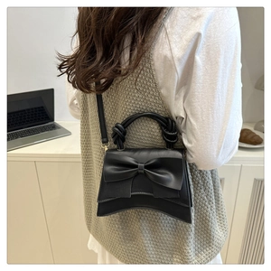 Close-up of black PU leather bag featuring a large decorative bow and knot handle detail