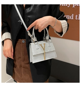Detail of silver crossbody bag with gold V logo and long tassel on shiny leather
