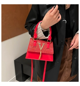 Detalle de bolso rojo con cristales brillantes y colgante dorado en forma de V con flecos