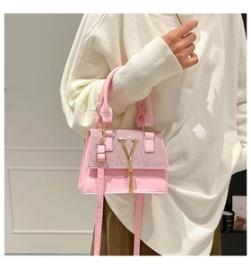 Detalle de bolso rosa con purpurina, logotipo en V dorado y colgante de borlas