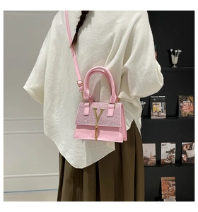 Pink crossbody bag with glitter flap and gold V pendant shown on a female model