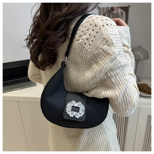 Détail du sac croissant noir avec plis verticaux et boucle ornée de cristaux scintillants