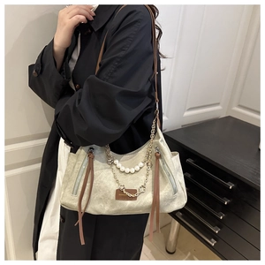 Détail du sac en toile avec bandoulière perle, breloques fleurs et zips latéraux