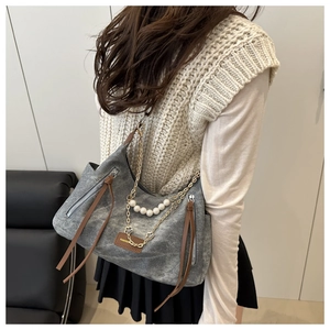 Détail du sac cabas en toile grise avec chaîne en perles et étiquette mode en cuir