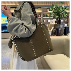 Gros plan du sac cabas en toile vert olive avec rivets argentés et bandoulières