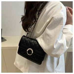 Detail view of quilted leather crossbody bag with pearl buckle and metal chain strap