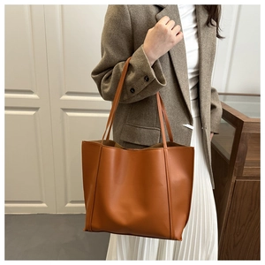 Detail of a large vintage orange tote bag in soft leather texture on female model