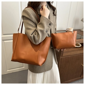 Close-up of caramel brown leather tote bag and matching clutch set on a shoulder