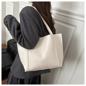 Minimalist cream white PU leather tote bag shown on shoulder for size reference