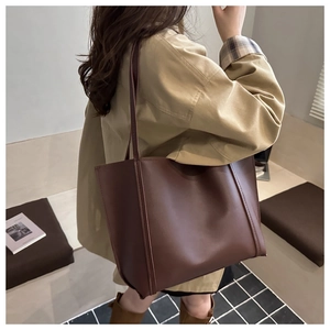 Detailed view of deep brown large capacity tote bag worn on shoulder by a model