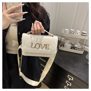 Close-up of beige quilted bag featuring a golden LOVE letter buckle and chain strap