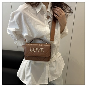 Close-up of brown quilted crossbody bag featuring gold LOVE lettering and wide strap
