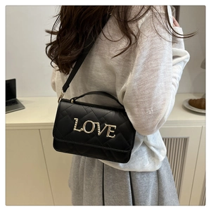 Detail of black quilted crossbody bag featuring golden rhinestone LOVE buckle on flap