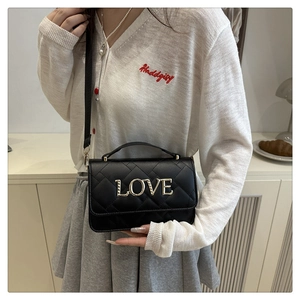 Detail of black quilted leather pillow bag featuring gold metal LOVE letter charms