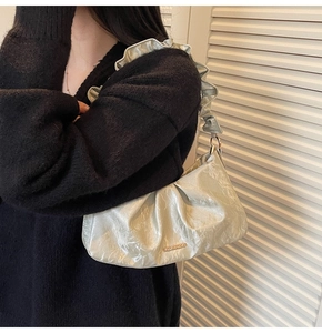 Close-up of silver pleated shoulder bag with metallic finish and ruffled strap detail