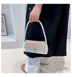 Detail of white and beige crocodile embossed leather handbag with gold metal clasp