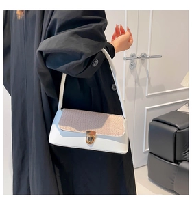 Dettaglio borsa baguette bicolore in pelle bianca e patta beige con motivo a coccodrillo