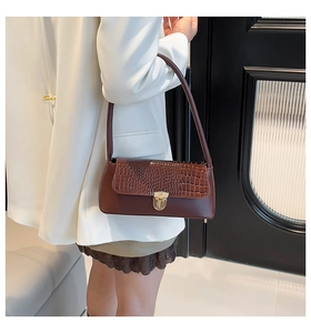 Detailed shot of brown baguette bag with crocodile texture and gold metal buckle closure