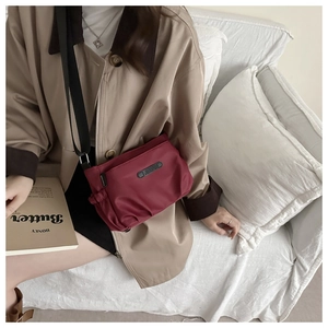 Close-up of red nylon pleated crossbody bag with JINGPIN brand logo on an adjustable strap