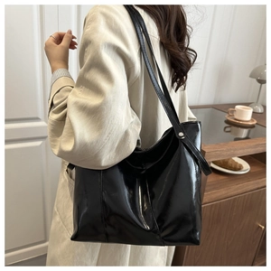 Gros plan du cabas noir brillant avec rivets argentés et texture en cuir verni