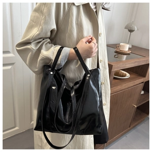 Mannequin portant un grand sac cabas noir brillant avec double bandoulière
