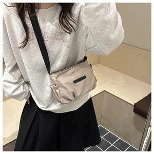 Detail of minimalist champagne nylon crossbody bag with side drawstring and black strap
