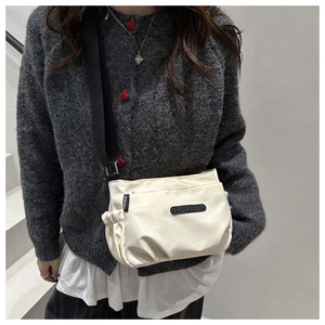 Detail of the cream nylon crossbody bag with side pocket and adjustable strap