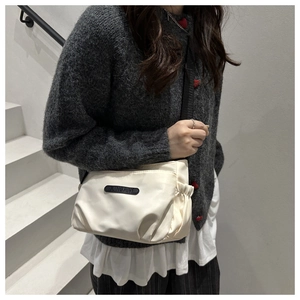 Close-up of off-white nylon shoulder bag with black JINGPIN label and ruched side details
