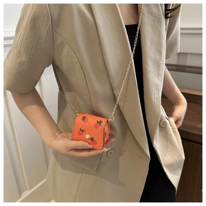 Détail du mini sac orange à imprimé fraise avec bandoulière chaîne dorée et cuir grainé