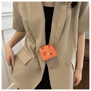 Gros plan du petit portefeuille orange à imprimé cerise avec chaîne dorée
