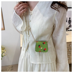 Mini sac bandoulière vert imprimé fraises avec chaîne dorée porté par un mannequin